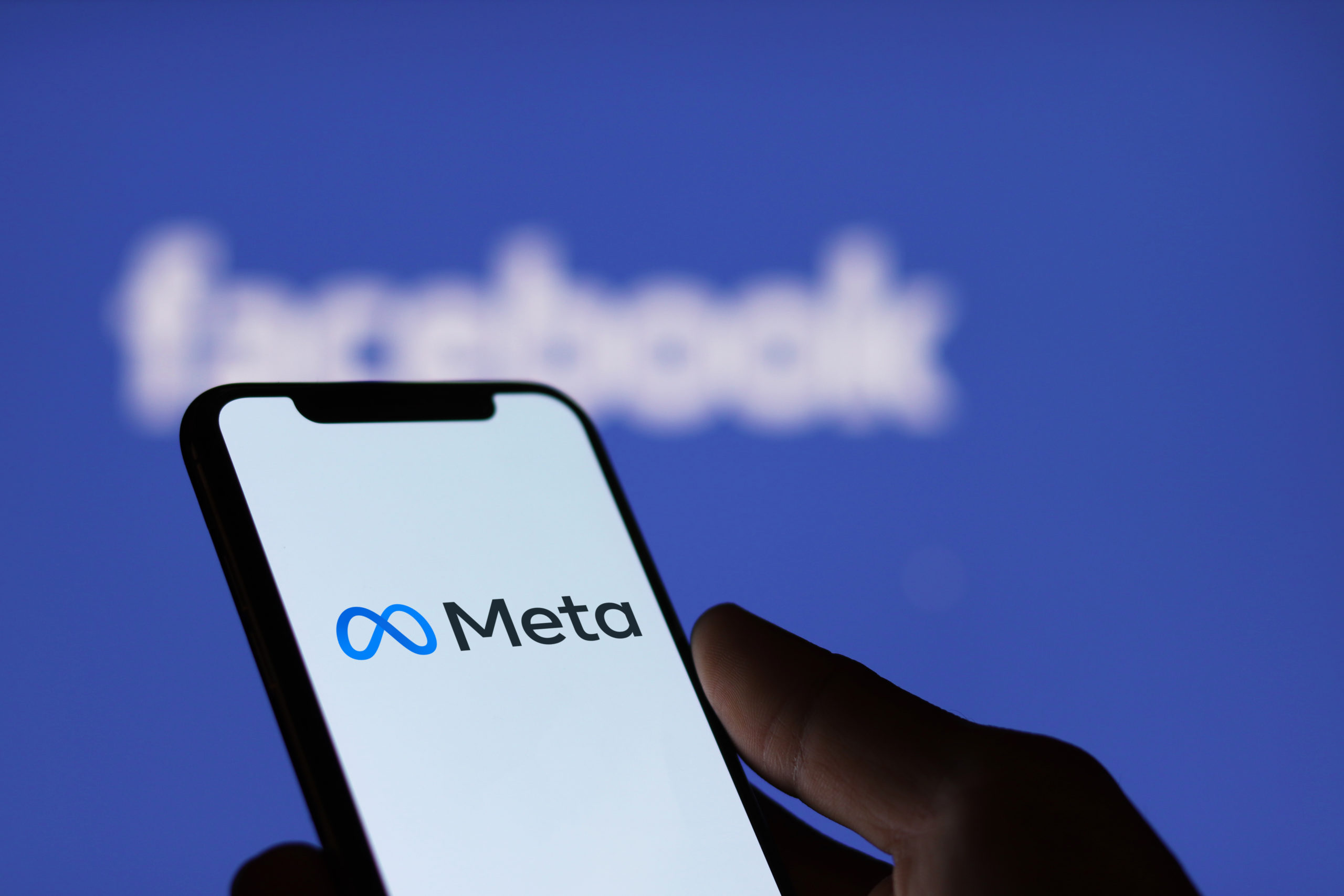 Meta logo on smartphone screen and Facebook logo background : C